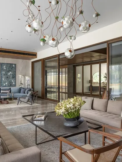 The expansive living room of the K Residence, designed to be both a grand space for entertaining and an intimate family area. The design incorporates large sliding doors to flood the room with natural light and features custom furniture and curated art, including exquisite Bocci lights.