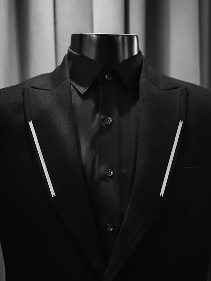 A mannequin displaying a black suit from our 'Metal Bling' collection, showing the sharp, clean lines of the metal inserts on the lapels.