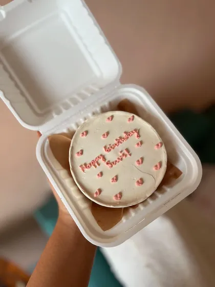 A minimalist bento cake with a simple "Happy Birthday" message and tiny piped hearts. It's a classic choice for any celebration.