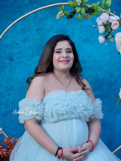A happy and confident portrait of the mother-to-be. Her bright smile radiates joy in this lovely blue-themed studio setup.