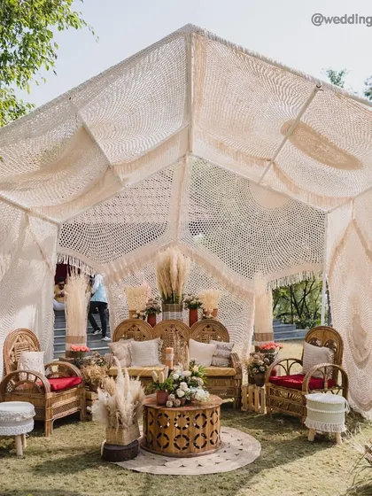 A serene welcome under woven dreams. We styled this bohemian mehendi lunch with a large macrame canopy, earthy-toned cane furniture, and curated pampas arrangements for a touch of organic elegance.