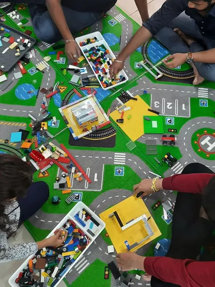 An aerial view of multiple teams working on their LEGO projects. This demonstrates how our workshops can accommodate several groups working simultaneously on different challenges.