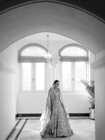 A stunning black and white portrait of the bride, Nishna, in the corridors of the Taj Mahal Palace. The architectural arches and natural light create a timeless and elegant frame.