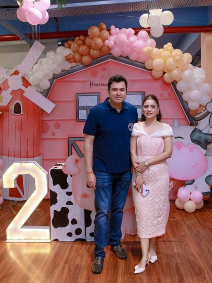 The proud parents of the birthday girl stand before their beautifully executed barnyard theme decor. We work closely with clients to bring their vision to life.