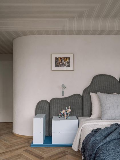 A detail shot of the master bedroom, focusing on the curved wall and custom headboard.