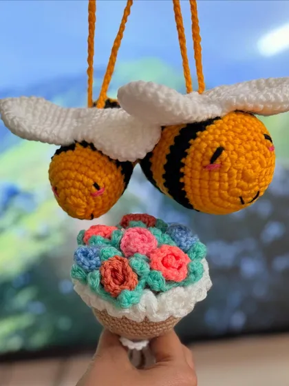 Bring a little buzz of happiness to your car or home with these adorable hanging decorations. This set features two smiling amigurumi bees and a tiny bouquet of colorful flowers, all crocheted by hand.