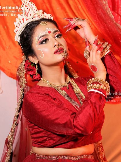 A graceful pose that showcases the entire look, including the red Banarsi saree and traditional jewelry. The makeup is designed to be long-lasting and vibrant.