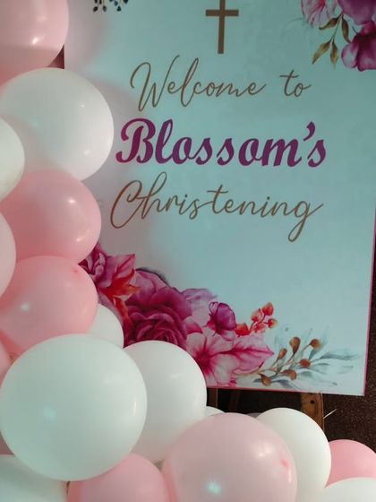 The personalized welcome sign for 'Blossom's Christening', surrounded by pink and white balloons at the entrance.