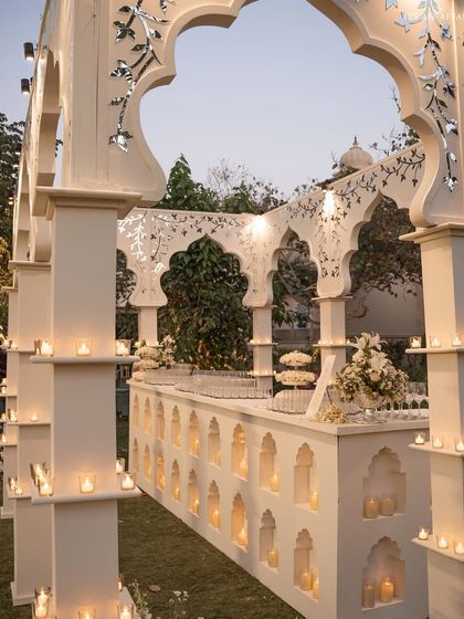 A close-up of the custom 'Sheesh Mahal' bar, featuring intricate arches, mirror inlays, and dozens of candles set within its niches.