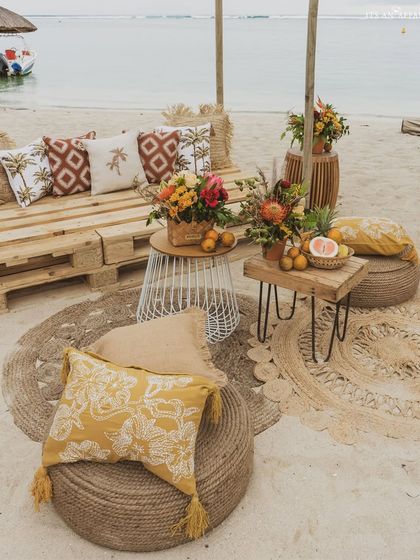 A casual seating area on the sand, with jute poufs and pallet furniture, creating a relaxed, bohemian vibe.