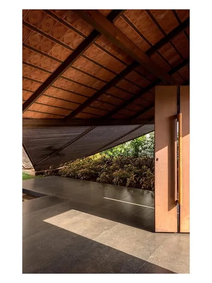 Light filters through the gaps in the pavilion roof, creating a rhythmic pattern on the floor. The design pays close attention to the quality of light and shadow.
