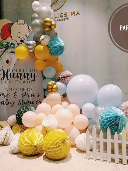 A "Little Hunny" Winnie the Pooh themed baby shower with a custom welcome sign, and a mix of balloons and paper honeycomb balls.