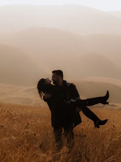 A dramatic and romantic silhouette against the soft, rolling hills at dusk. This image captures a feeling of adventure and togetherness, portraying the couple as the heroes of their own epic love story.