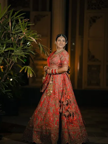 A stunning full length portrait of a bride in her magnificent red lehenga, captured at night to create a dramatic and elegant look.