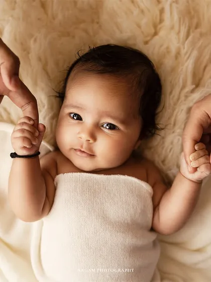 A close-up of a newborn holding her parents' fingers. This shot is all about connection and the beginning of their journey together.