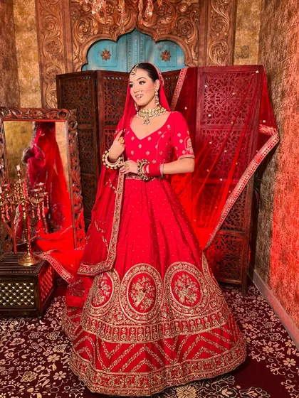 A full-length view of a traditional red bridal lehenga. The grand skirt and matching dupatta create a majestic silhouette that will make you feel like royalty.