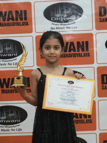 A young student in a black dress proudly holds her award.