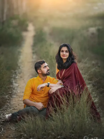 A couple seated in a grassy lane, sharing a quiet moment. The warm, golden light and natural setting create a romantic and dreamy atmosphere for this portrait.