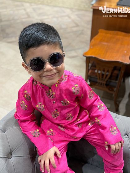 A playful shot of our little client in a bright pink printed kurta, showing off his cool sunglasses and even cooler attitude.