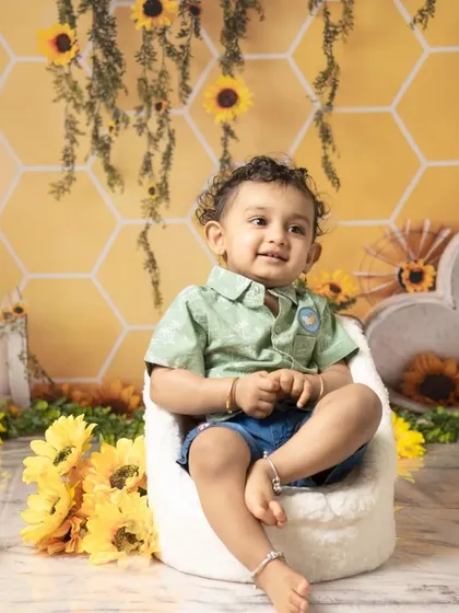 This little boy looks thoughtful before diving into his sunflower-themed cake smash. The yellow and green setup creates a bright and cheerful atmosphere.