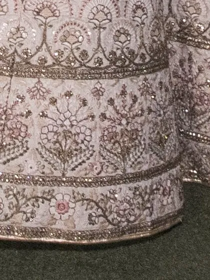 A close-up of the heavy embroidery on the hem of the ivory lehenga skirt. The multi-layered patterns showcase the quality craftsmanship of this rental piece.