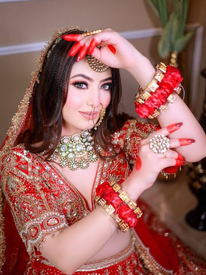 A vibrant portrait of a bride with traditional alta on her hands, posing playfully for the camera.