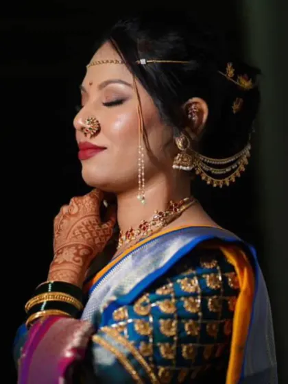 A side profile showcasing the complete Maharashtrian bridal look. You can see the detailed eye makeup, the elegant hairstyle with traditional accessories, and the iconic 'nath' that completes the look.