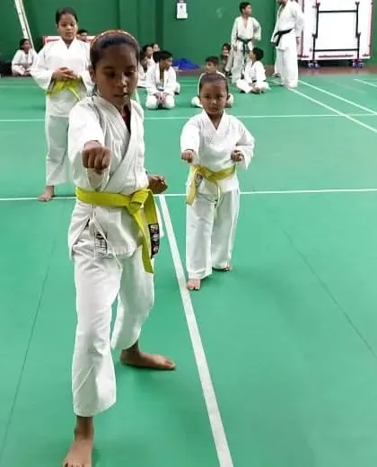 A young student with a yellow belt demonstrates a strong forward stance and punch, showing excellent basic form.