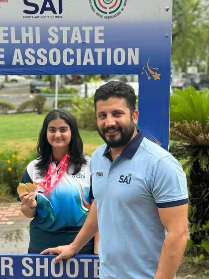 Posing with a gold medalist outside the Dr. Karni Singh Shooting Range. We train our athletes to be competitive at Delhi's premier shooting venues.