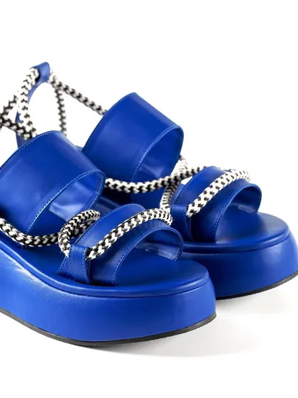 A close-up detail shot of Jeetinder Sandhu's vibrant blue platform sandals. This e-commerce style photo on a clean white background highlights the unique design, rope-like straps, and quality construction of the footwear.