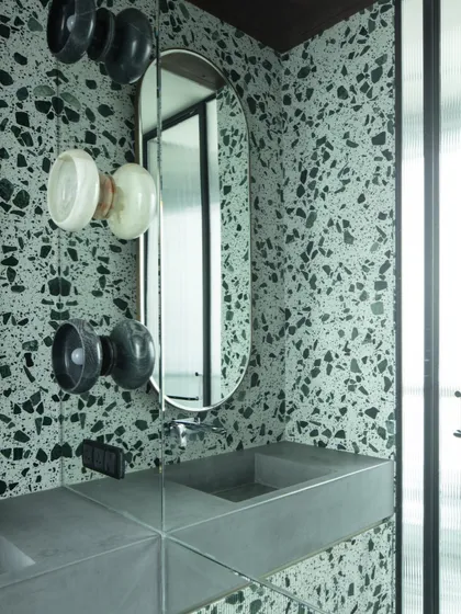 A detail of the terrazzo-clad bathroom, showing the hand-chiseled stone wall lights we designed. The combination of modern materials and handcrafted details creates a unique and sophisticated space.