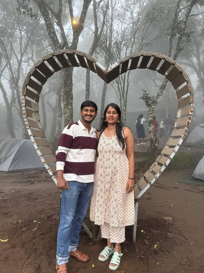 A couple posing in front of a heart-shaped installation in a misty campsite in Munnar.