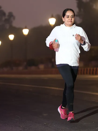 A female runner looking strong and focused during a night-time or early morning run.