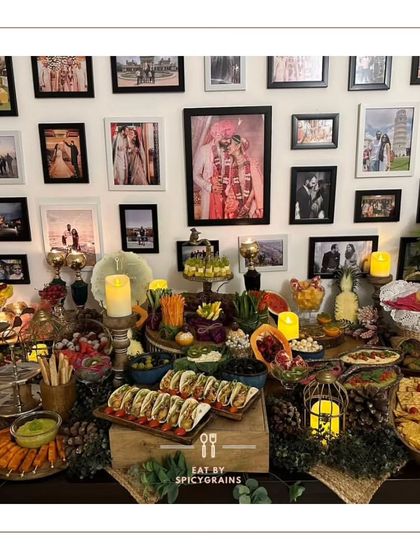 We create a feast that complements your home's warmth. This grazing table is set against a beautiful gallery wall, blending seamlessly into the party's atmosphere with an array of tacos, dips, and fresh fruits.