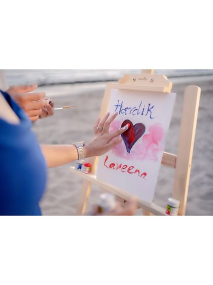 A close-up detail shot of the couple painting a heart on a canvas during their beach photoshoot. Incorporating personal activities like this makes the session more meaningful and unique.