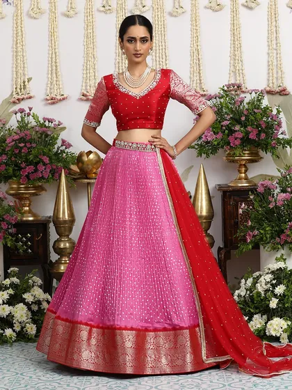 This pink Bandhani lehenga with a red blouse is a perfect example of how we fuse timeless drapes with bold silhouettes.