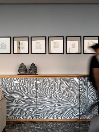 A custom-designed credenza with a graphic black and white pattern serves as a focal point in this lounge on the director's floor of the Stainless Steel Office. The space is curated with unique art and furniture pieces.