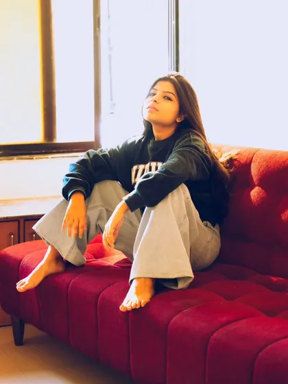 A full-body casual pose on the sofa, perfect for showcasing a relaxed, everyday style.