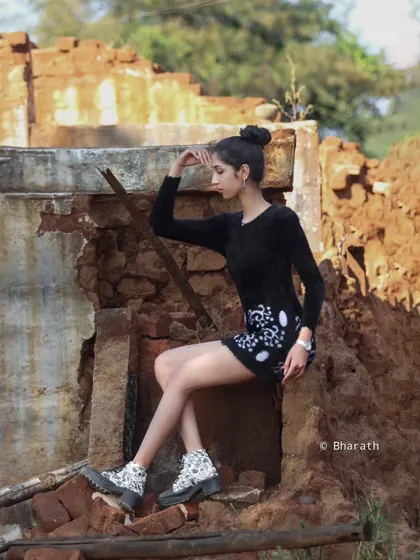 A seated pose that shows off the stylish boots and the contrast between the modern outfit and the ancient-looking ruins.