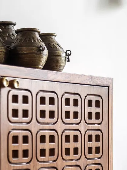 The detailed jaali work on the teak media cabinet, reflecting the coffered ceiling pattern and showcasing our commitment to cohesive design elements.
