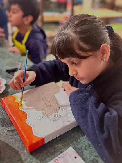 Another student carefully outlines her Mexican church design before starting to paint. This project teaches sketching, composition, and color blocking.
