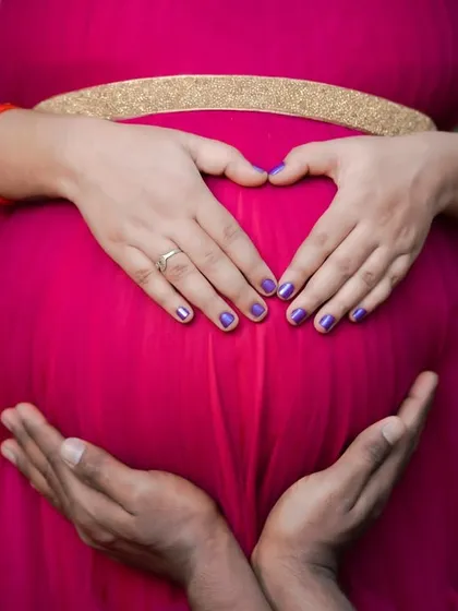A close-up shot focusing on the hands of both parents forming a heart around the baby bump. This symbolic gesture is a beautiful way to represent their shared love and protection.