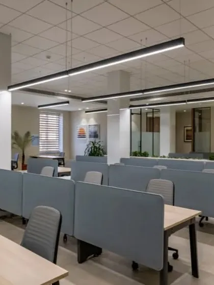 This view shows the flow from the open work area to private offices in the background. The consistent design language ensures the entire floor feels like a single, cohesive space.