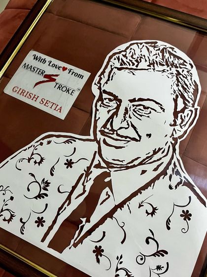 A close-up of the framed Madan Mohan portrait. The floating frame allows you to see through to the wall, making the white paper-cut design really stand out.