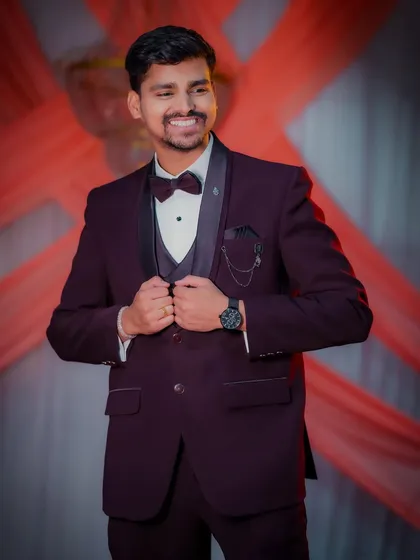 A dapper portrait of the groom, Nikhil, looking sharp in his maroon tuxedo and bow tie for his engagement ceremony. His confident smile shows his excitement for the day.