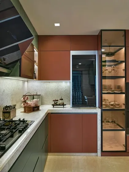 A bold and beautiful kitchen designed in collaboration with Milind Pai Architects, featuring a striking combination of red and green cabinets. The glass-fronted pantry unit adds a touch of lightness.
