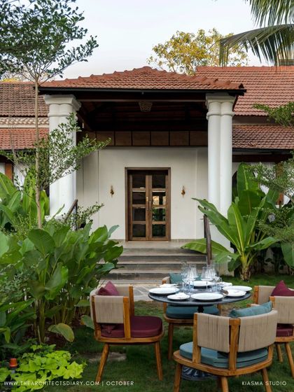An outdoor dining setup at Sanctuary Bar, with the restored Portuguese villa in the background. The landscape design creates a garden-like setting for the restaurant.