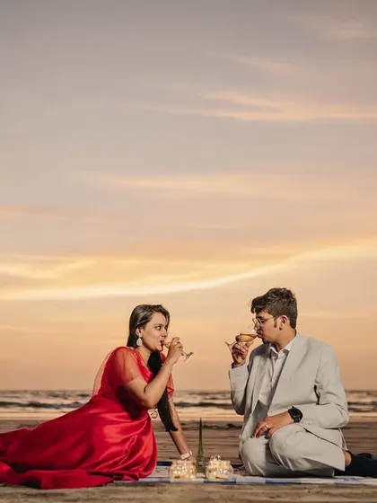 A candid moment of laughter and joy as the couple enjoys their sunset picnic on the sand.