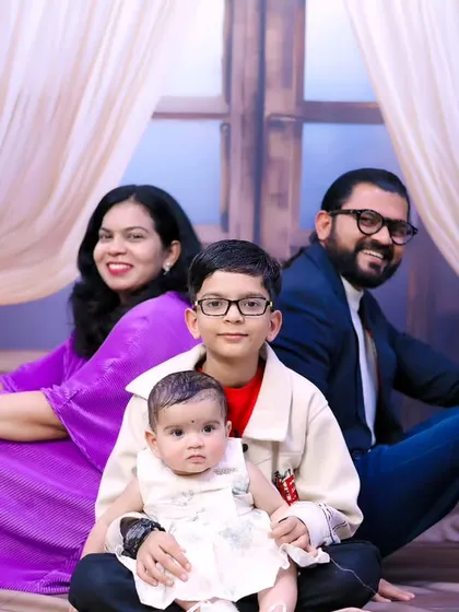 A relaxed and happy family portrait with parents, an older brother, and the new baby.