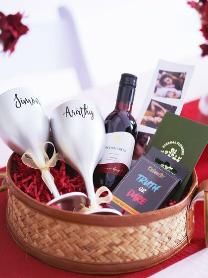 My 'Romantic Escape' hamper, featuring personalized wine glasses, non-alcoholic wine, and a game, all set in a beautiful round wicker basket.